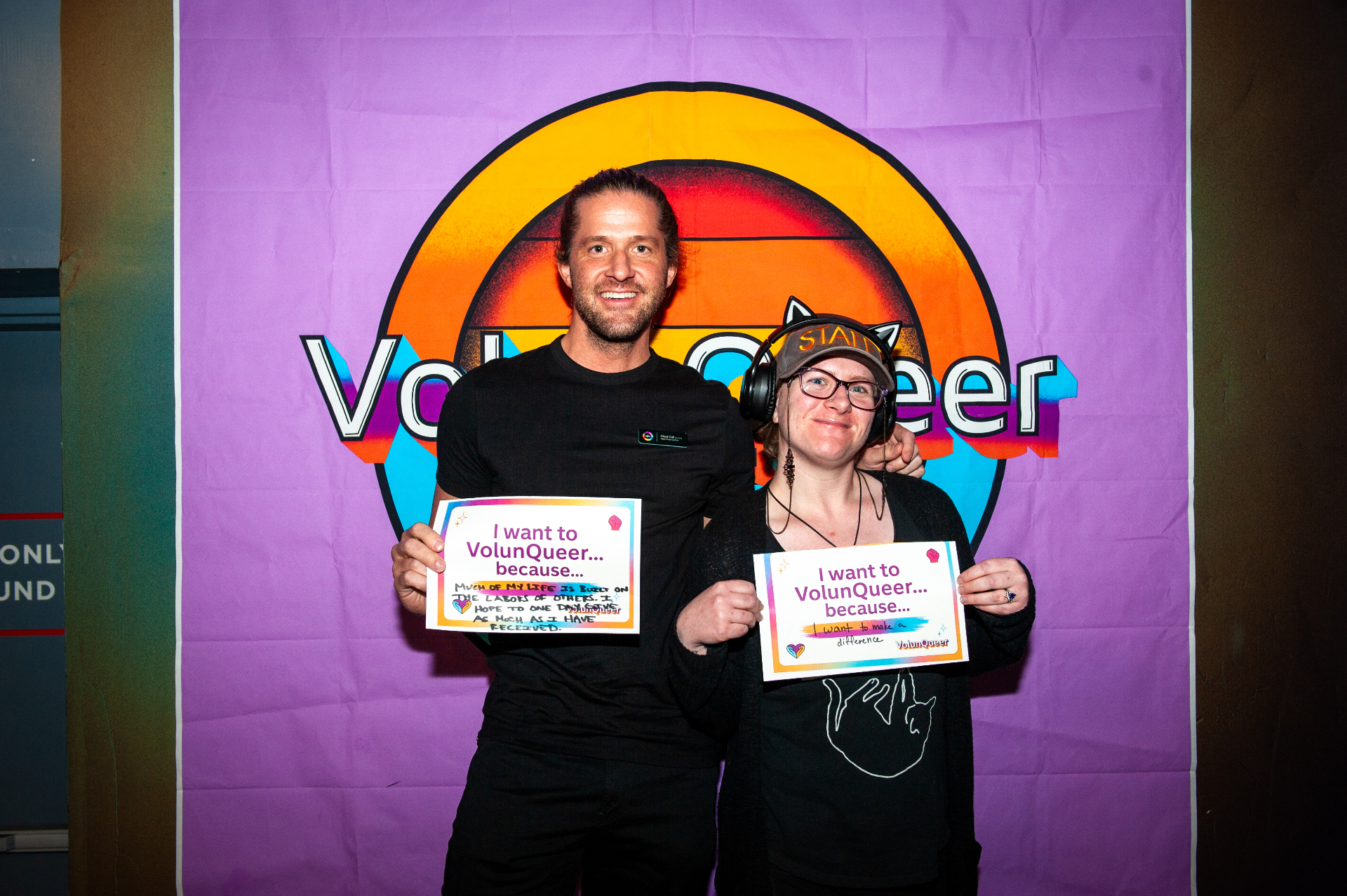 VolunQueer community members at a Pride event holding 'I want to VolunQueer because...' signs